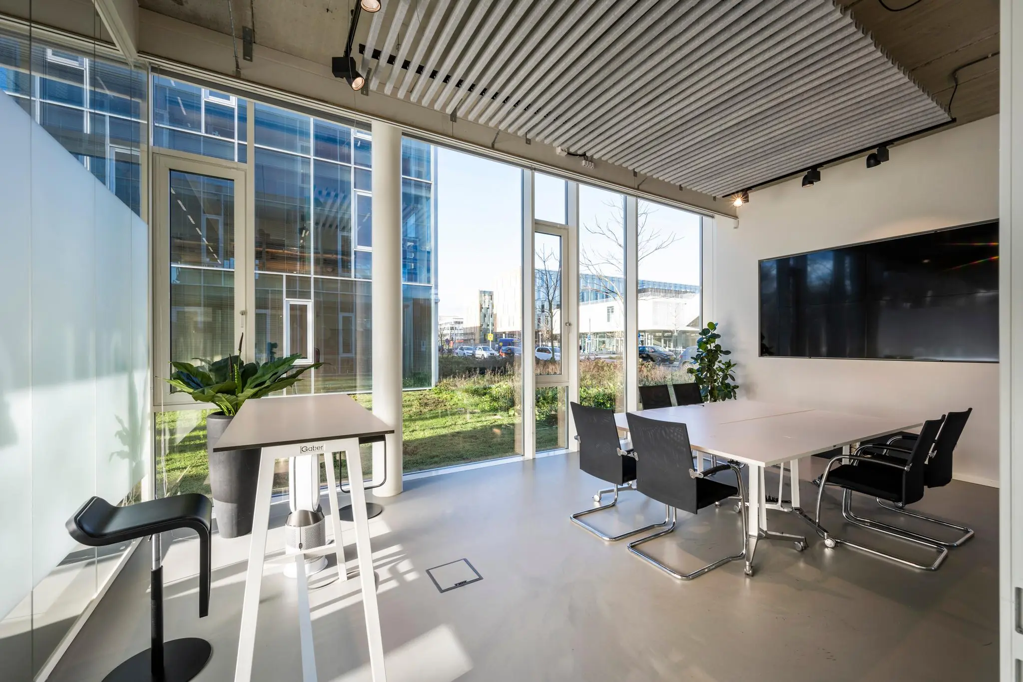 Moderne vergaderruimte aan de Fred. Roeskestraat met grote ramen, strakke meubels en een flatscreen aan de muur.